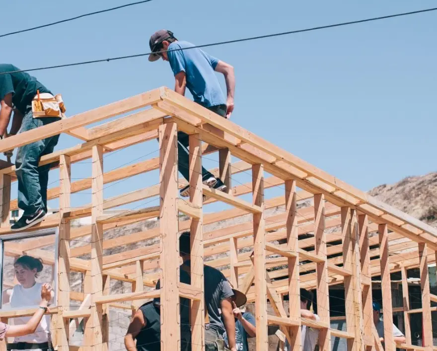 Construction crew framing the wooden roof structure of a new residential project by RealtyZoom.